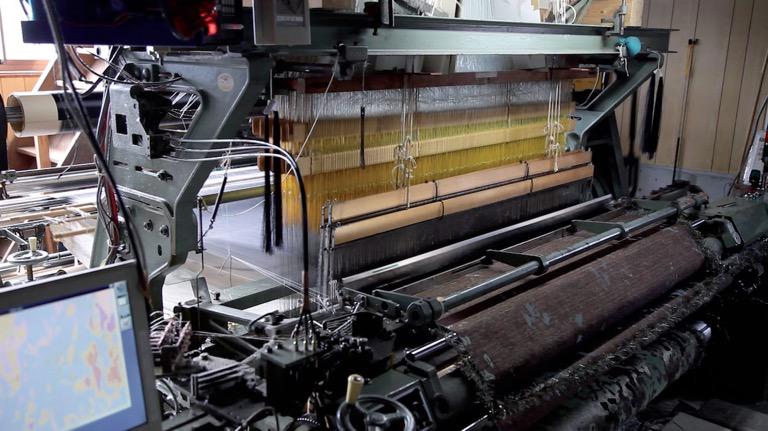 The carpet being woven on a Jacquard loom. Ken Furudate
(programmer) developed a program to automate the process of reducing the colors in the original picture.